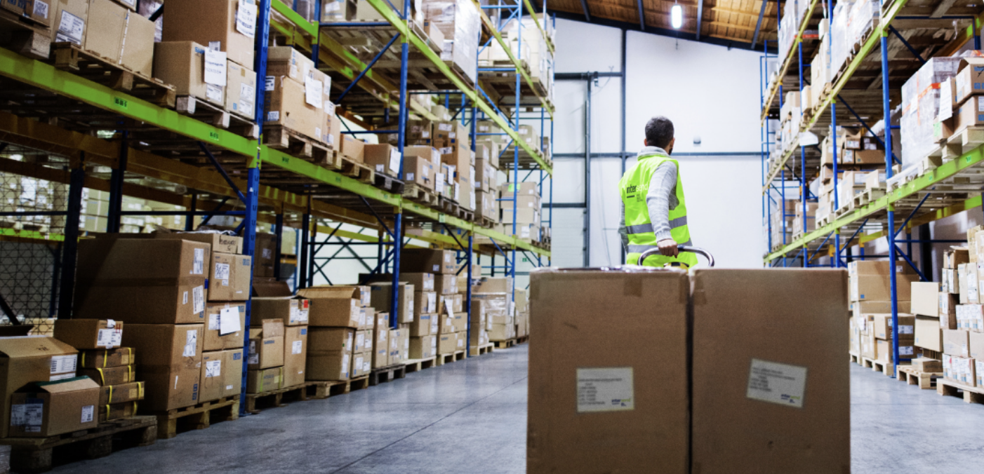 worker in a warehouse carting large boxes